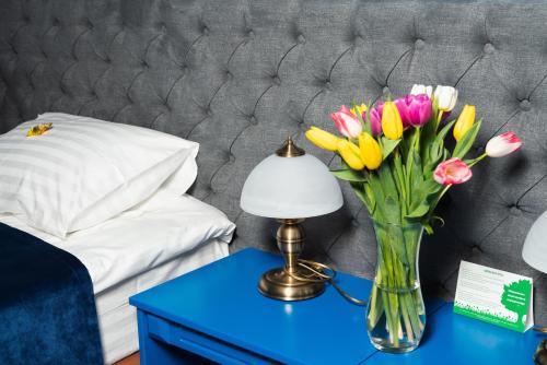 a vase of flowers on a table next to a bed at Fontush Boutique Hotel in Ivano-Frankivsʼk