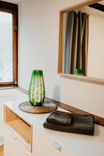 a green vase sitting on top of a counter with a mirror at Fachwerkhäuschen in Enkirch