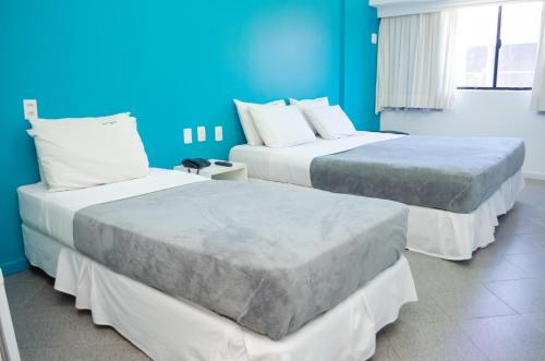 two beds in a room with blue walls at Bahia Sol e Mar in Salvador