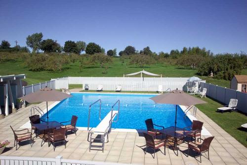 una piscina con mesas, sillas y sombrillas en Manoir d'Youville, en Châteauguay Heights