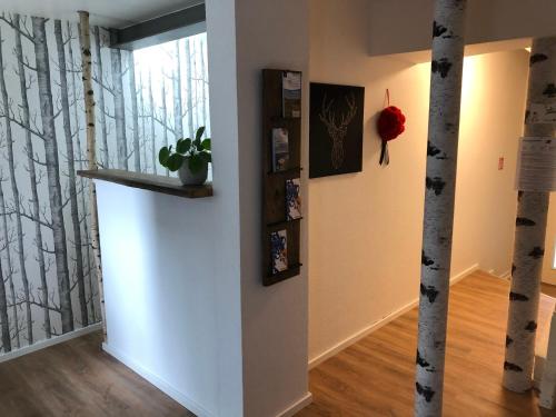 a hallway with a white wall with trees on it at Black Forest Bike Hostel in Kirchzarten