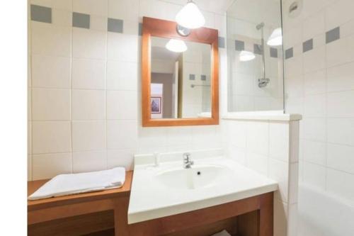 une salle de bain avec un lavabo et un miroir dans l'établissement Appartement près lac et océan, à Carcans