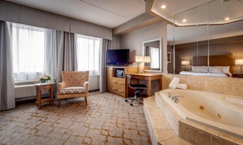 Habitación de hotel con bañera, escritorio y cama en Monte Carlo Inn Vaughan Suites, en Vaughan