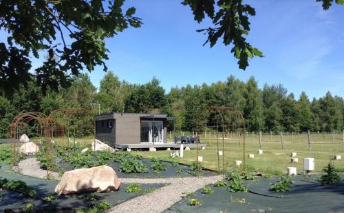 a tiny house in a field with trees in the background at Cottage tout confort au milieu des chevaux in Saint-Fargeau