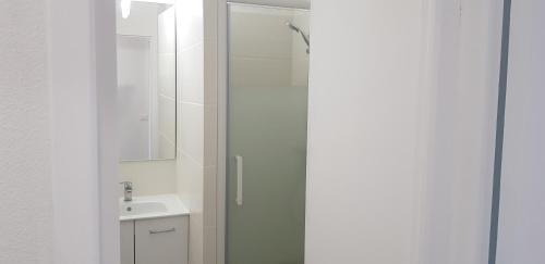 ein weißes Bad mit einer Dusche und einem Waschbecken in der Unterkunft Sables Blancs-DZ in Douarnenez
