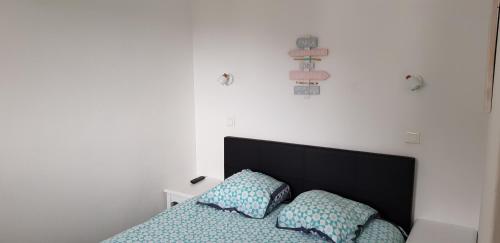 ein Bett mit einem schwarzen Kopfteil und zwei Kissen in der Unterkunft Sables Blancs-DZ in Douarnenez