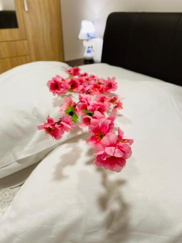 a bunch of pink flowers sitting on a bed at Central Square Apartment 2 in Pýrgos