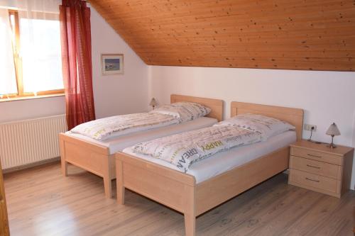 2 Betten in einem Schlafzimmer mit Holzdecke in der Unterkunft Ferienwohnung im Rosengarten in Ebenweiler