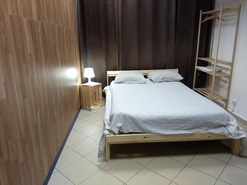 法魯的住宿－Melaya Budget Hostel，卧室配有一张床和一盏灯,铺有瓷砖地板。