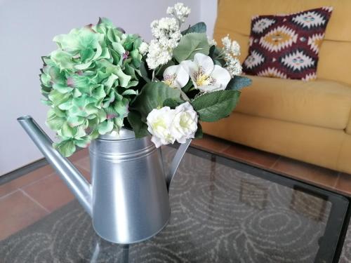 a metal vase with flowers on a coffee table at Casa Rural el Enebral en Potes Picos de Euopa in Colio