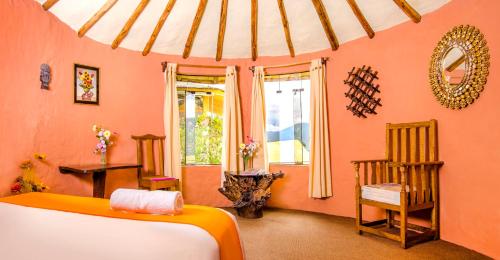 1 dormitorio con paredes de color naranja, 1 cama y 1 silla en Hotel Kuntur Wassi en Cabanaconde