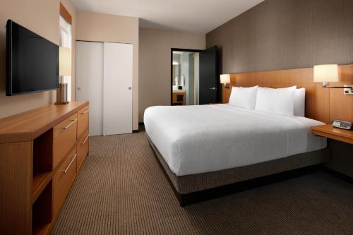 a hotel room with a large bed and a flat screen tv at Hyatt Place Calgary Airport in Calgary
