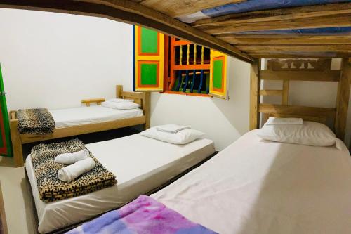 2 camas en una habitación con pinturas coloridas en la pared en casa hostal las palmeras, en Guatapé