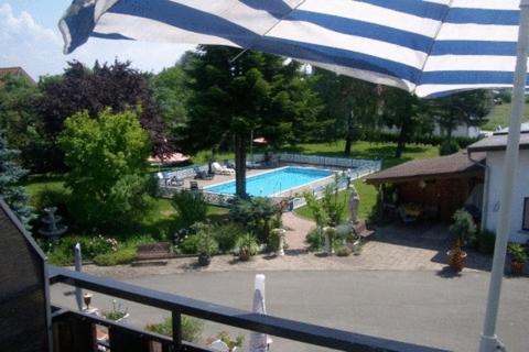 ein blauer und weißer Schirm über einem Pool in der Unterkunft Hotel Wegis Garni in Bermatingen