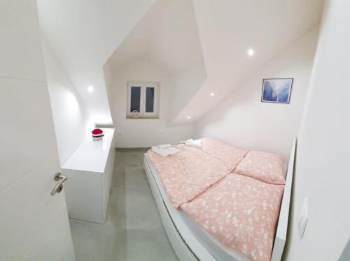 a white room with a bed with pink sheets at Villa Marija in Splitska