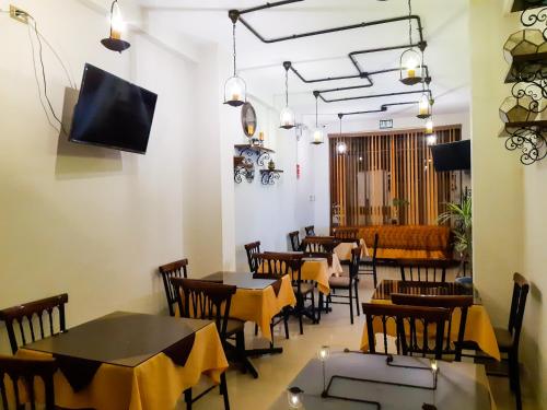 a restaurant with tables and chairs and a flat screen tv at Retama Hotel in Tacna