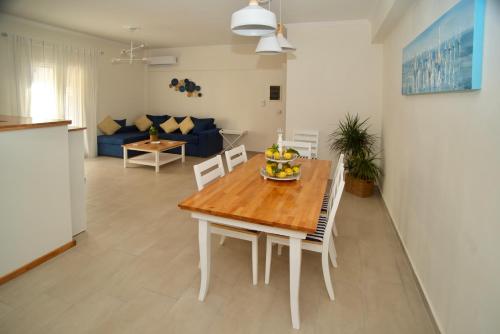 a kitchen and living room with a wooden table and chairs at The Bluehouse - Spacious top floor flat with parking, by Mon Repos beach in Corfu