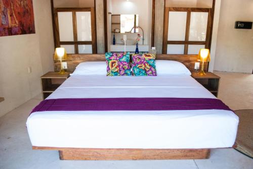 a bedroom with a large white bed with pillows at Hotel Pochote Mazunte in Mazunte