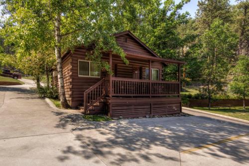 a log cabin with a porch and a tree at Powder House Lodge in Keystone
