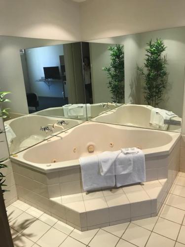 a large bathroom with a tub and a mirror at Bay Motel Hotel in Adelaide