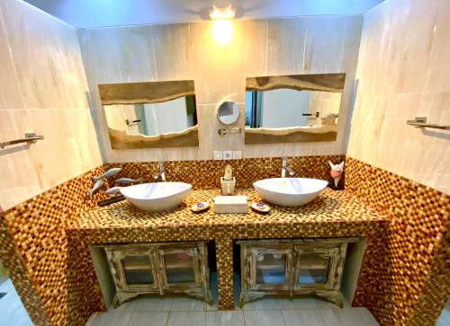 un baño con dos lavabos y dos espejos en Cinta Cottages, en Gili Trawangan