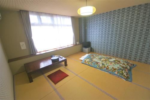 a room with a bed and a table and a window at Sakurakan in Minami Kyushu