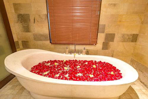 a bath tub filled with red flowers in a bathroom at Alamdini Resort Ubud in Ubud