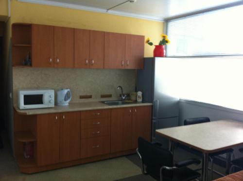 a kitchen with wooden cabinets and a table and a microwave at Molodizhniy Hostel in Lviv