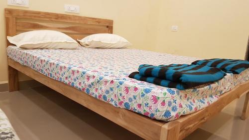 a bed with a wooden frame and pillows on it at Godwill Kimo Guest house Seraulim in Madgaon