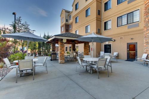 a patio with tables and chairs and umbrellas in front of a building at Staybridge Suites Missoula by IHG in Missoula