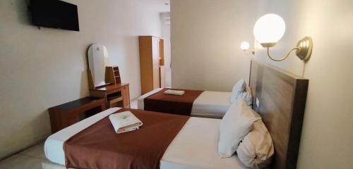 ein Hotelzimmer mit 2 Betten und einem TV in der Unterkunft Tiara Inn in Ternate