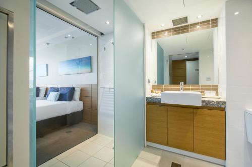 a bathroom with a sink and a bed and a mirror at The Ville Resort - Casino in Townsville