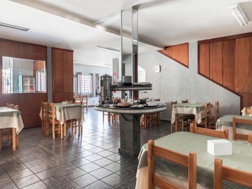 a restaurant with tables and chairs and a kitchen at Hotel dos Nobres in Poços de Caldas