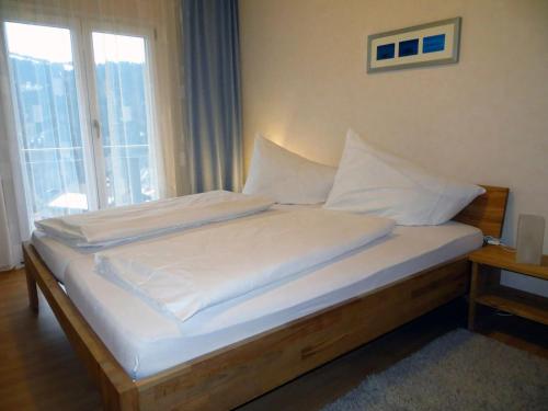 a bed with white sheets and pillows in a room with a window at Haus Matt in Laterns