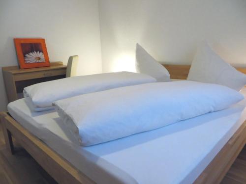 a bed with white sheets and pillows on it at Haus Matt in Laterns