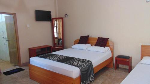 a bedroom with two beds and a television in it at Hotel Alas Garden in Trincomalee