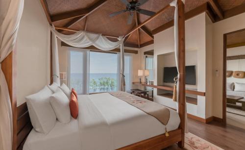 Crimson Resort and Spa - Mactan Island, Cebu في ماكتان: غرفة نوم بسرير كبير مع نافذة كبيرة