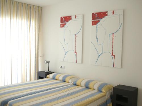 um quarto com uma cama e duas pinturas na parede em Apartamentos Rodamar em L'Estartit