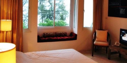 a bedroom with a bed and a window and a chair at Cha_Inn @ Cha Am in Cha Am