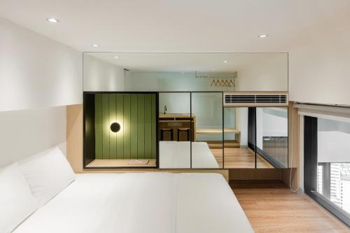 a bedroom with a white bed and a kitchen at Komune Living in Kuala Lumpur