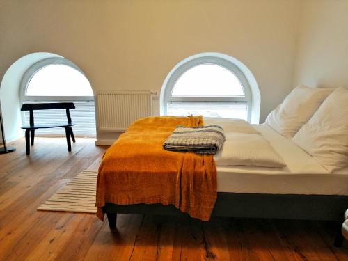 een bed met een oranje deken en twee ramen bij REMA Apartments Lustkandlgasse in Wenen