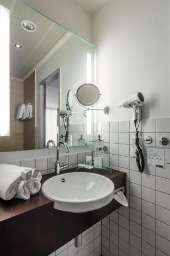a bathroom with a sink and a mirror at Hotel Esplanade Dortmund in Dortmund