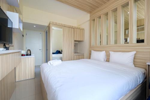 a bedroom with a large white bed and a kitchen at Elegant Studio Apartment at Bogorienze By Travelio in Bogor