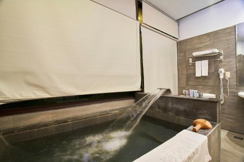 a bathroom with a bath tub with a sink at A-SAN Hot-Spring Hotel in Jiaoxi