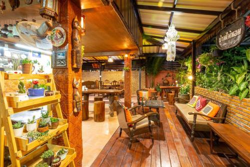 un restaurante con mesas, sillas y plantas en Baan Maihorm Guesthouse, en Mae Chan