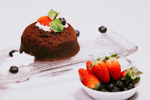 a chocolate cake with berries and a bowl of strawberries at Anik Palace Hotel in Phnom Penh