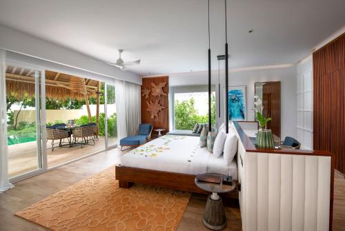 sypialnia z łóżkiem, stołem i krzesłami w obiekcie Emerald Maldives Resort & Spa-Deluxe All Inclusive w mieście Raa Atoll