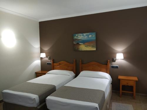 2 camas en una habitación con 2 lámparas en la pared en El Eden, en El Ejido