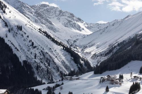 a mountain covered in snow with houses and trees at Landhaus Panorama in Berwang