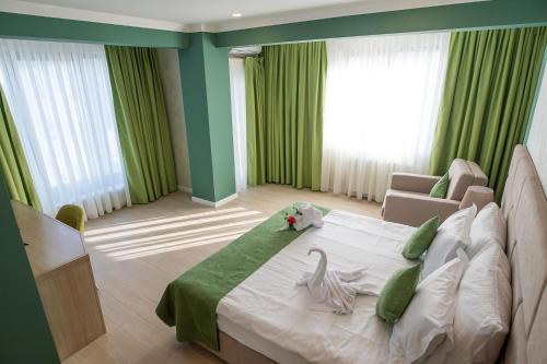 a bedroom with a large bed with a green wall at Hotel Azaleea Mamaia Nord in Mamaia Nord